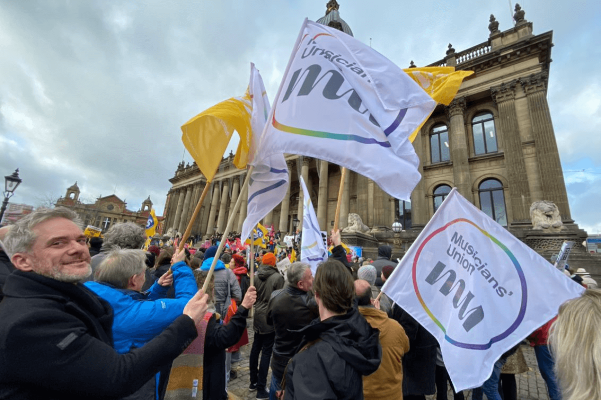 Matt Wanstall holding an MU flag among a crowd of people at the Right to Strike March in Leeds