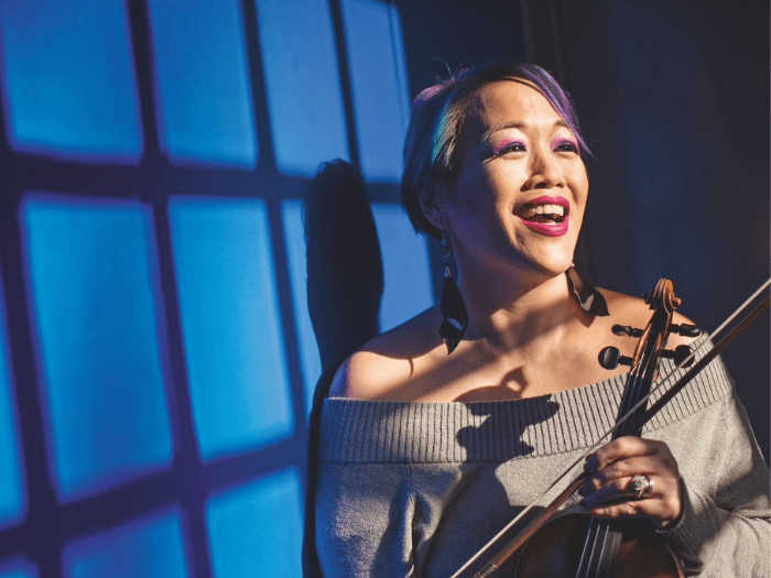 Portrait of Maxine Kwok smiling holding a violin.