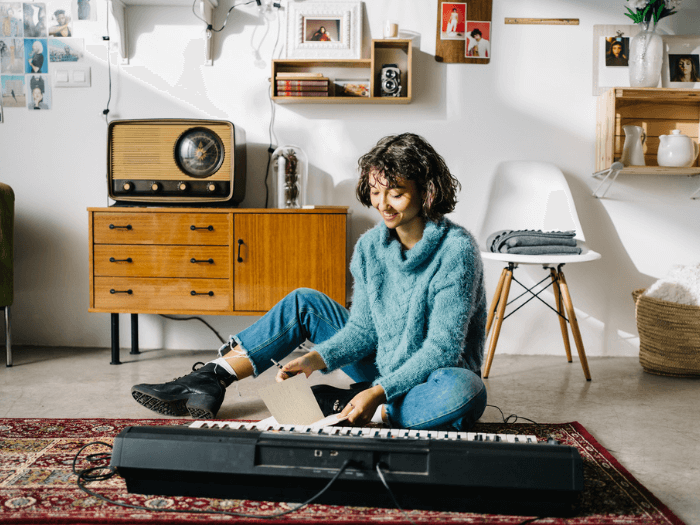 A young woman choosing composition for playing synthesizer at home.