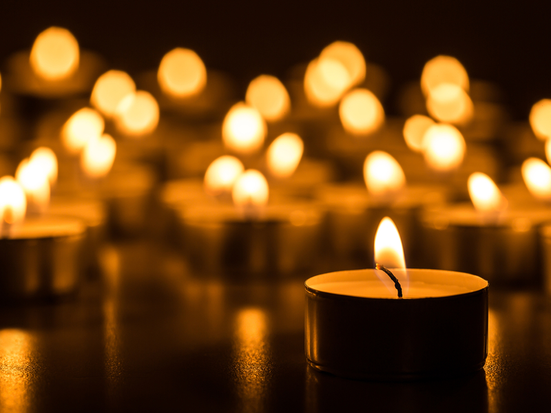 A collection of bright tealight flames against a dark background.