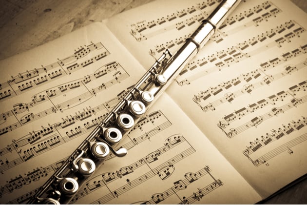 Photograph of a flute resting on a score, yellow lighting is shining down on everything.
