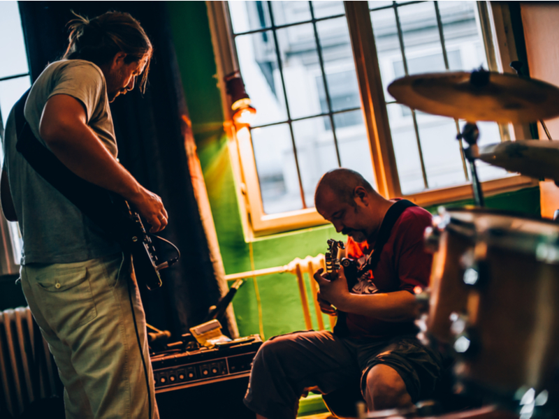 Two musicians both on guitar playing in what appears to be a small pub environment