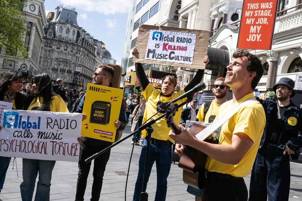 MU members and buskers gathered in a group holding signs and banners