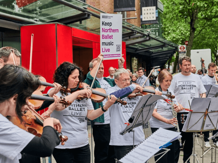 Members of the orchestra playing live outside before the performance, wearing T-shirts saying Keep Northern Ballet Live.