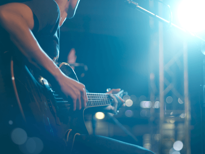 Close up of guitarist on stage, soft and out of focus.
