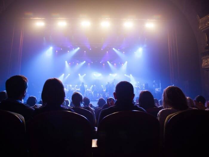 Silhouette of audience watching musicians on stage at a theatre.