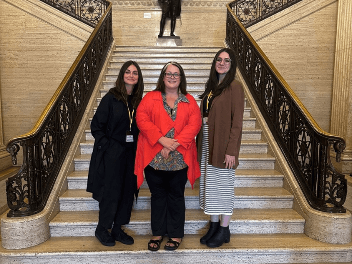 MU representatives and a politician standing on the steps at Stormont in Northern Ireland.