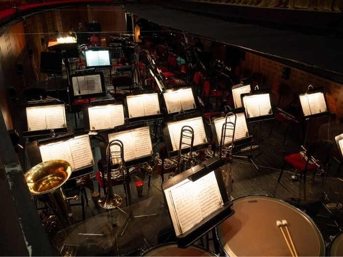 Instruments and music sheets in an empty orchestra pit with no players.