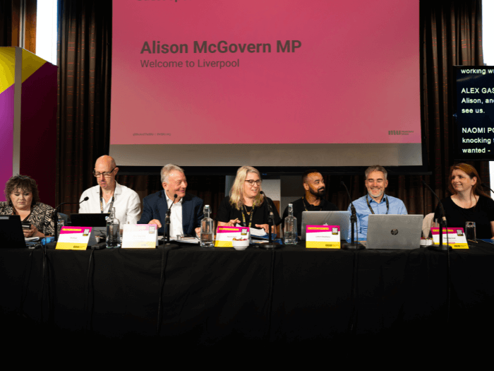 The top table at Conference on stage (Chair and Co-Chair of the Executive Committee, Chair of the Members’ Assembly, and the MU Secretariat team).