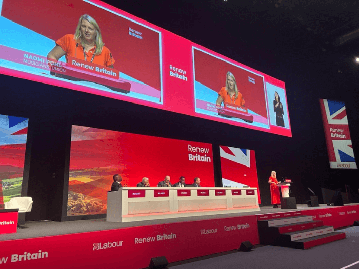 Naomi Pohl speaking on stage at a Labour Party Conference 2025