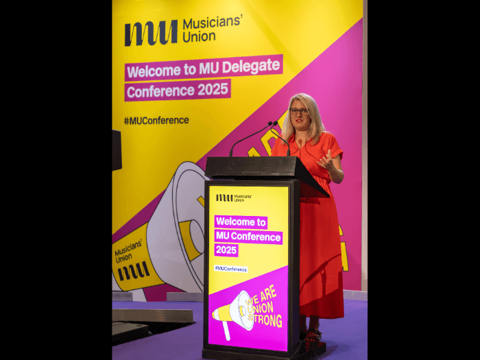 Naomi Pohl on stage addressing Delegates at Conference.