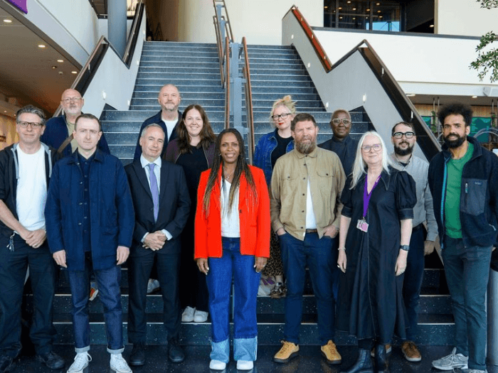13 members of the Board gathered in front of some stairs.