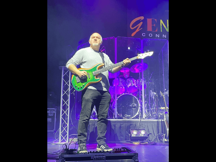 Nick performing onstage in front of a Genesis Connected banner.