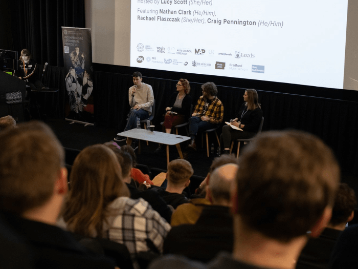 Some members of the Northern Music Network speaking at a panel event in front of a crowd.
