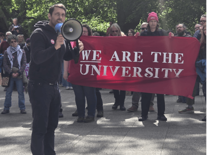People at the protest holding a red banner saying 