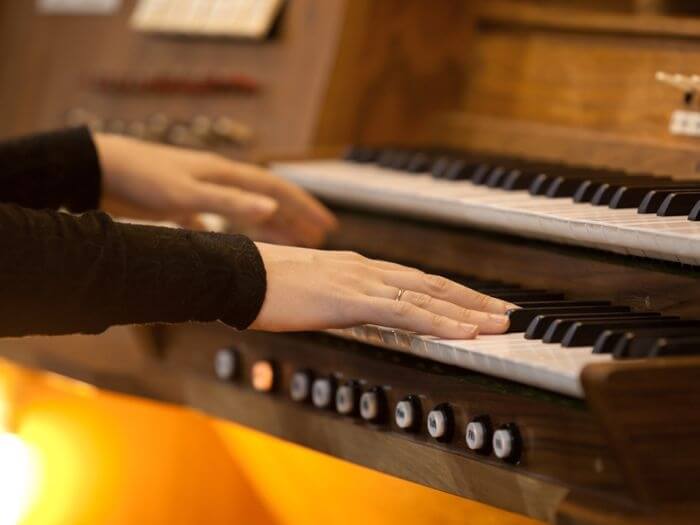Close up of a woman's hands playing an organ.
