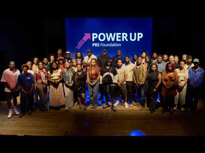 A group of music professionals standing in front of a backdrop to take a group photo.
