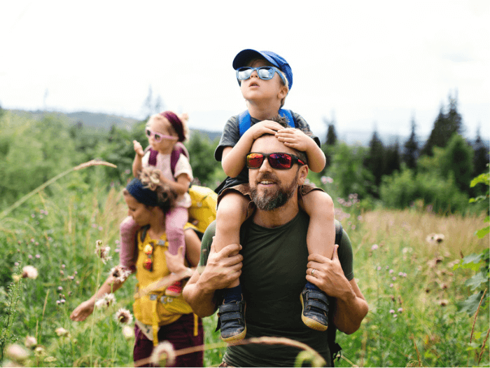 A family with two young children hiking in a field.