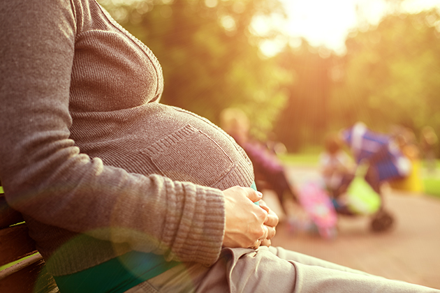 Photograph of pregnant woman sitting in a park.
