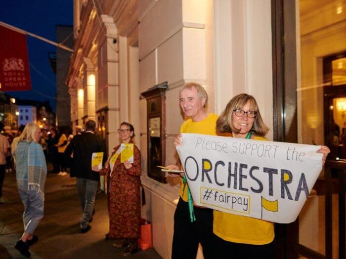 Members of the ROH Orchestra handing out flyers and holding a banner saying 'Please support the Orchestra #fairpay' before a performance earlier this month.
