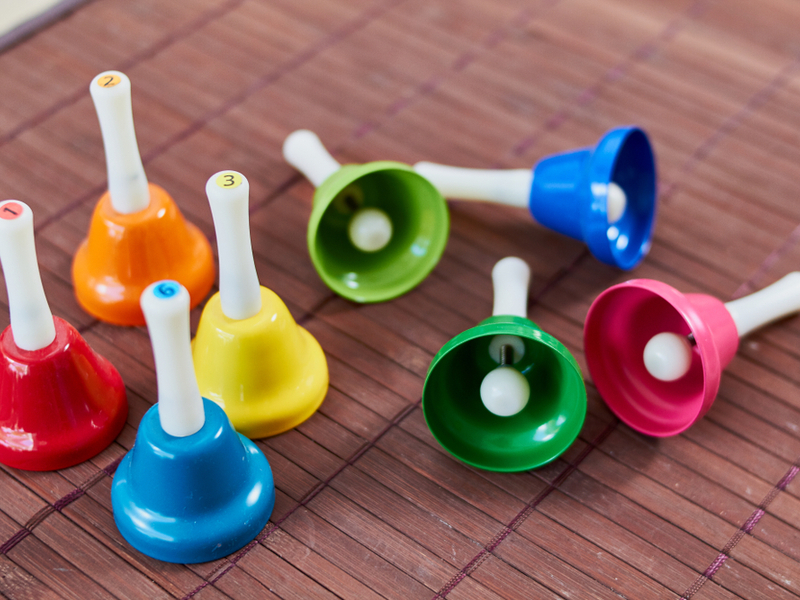 Multiple brightly coloured hand bells designed for children to play music with.