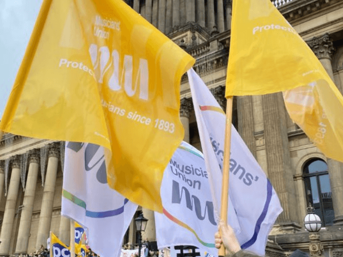 White and yellow MU flags being held by supporters outside of Leeds Town Hall for the Right to Strike march.