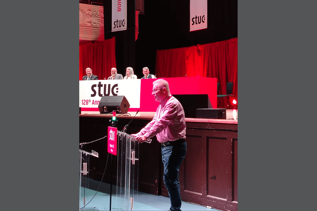 Ronnie MacNiven standing front of stage giving his speech to Congress.