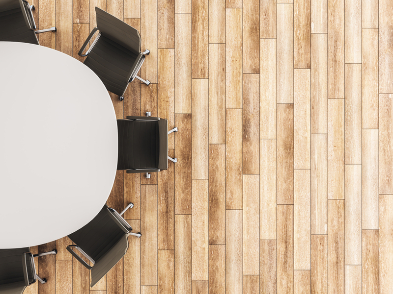 A birds eye view of a round table surrounded by chairs on a wooden floor.