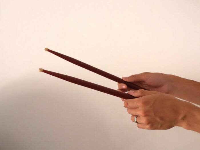 Pair of hands holding up drumsticks.