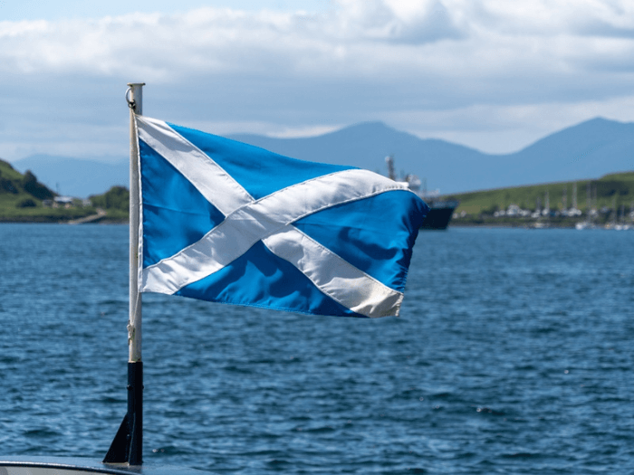 Waving flag of Scotland with Oban Bay in the background.