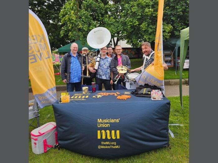 Members and visitors to last year's MU stall at the festival, holding instruments and banners.