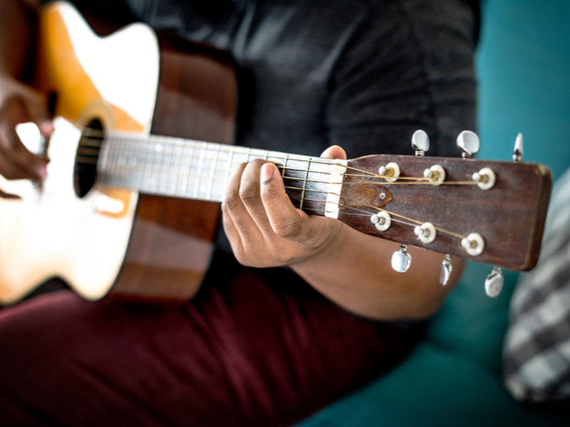 Photograph of a musician practicing on an acoustic guitar.