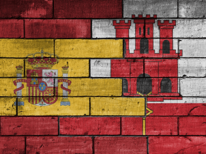 A brick wall with the flags of Spain and Gibraltar painted on it, overlapping each other.