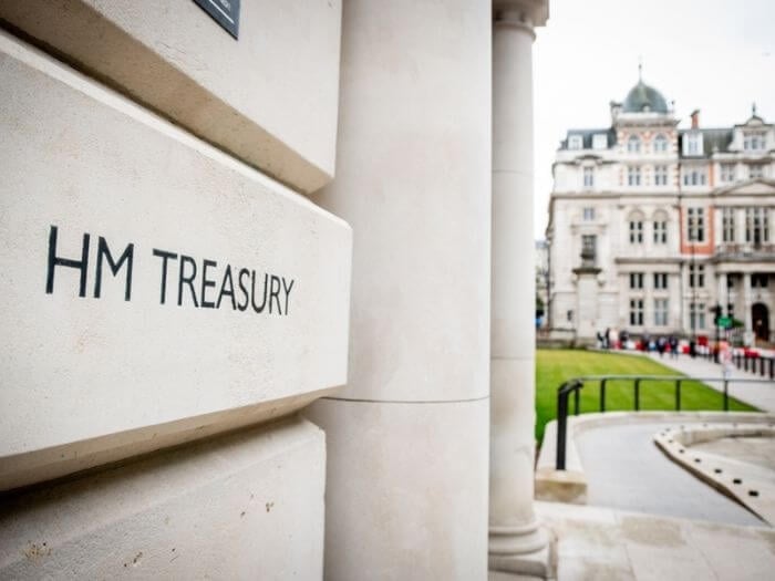 Close up of white government building in Westminster, London, with black words engraved into stone saying HM Treasury.