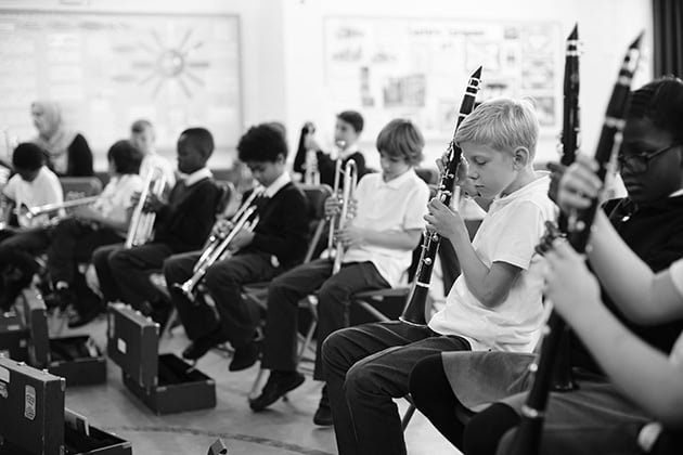 Children learning trumpet and clarinet in classroom setting