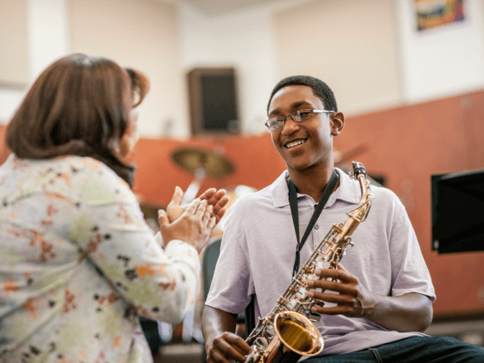 A music teacher with a student holding a saxophone.