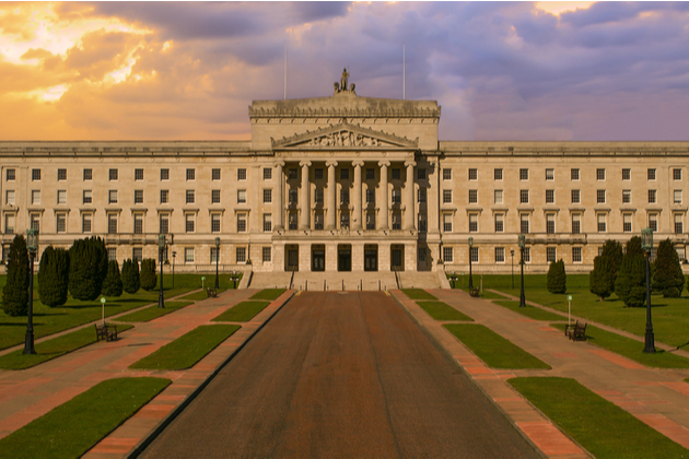 Photograph of the Parliament buildings of Northern Ireland, also referred to as Stormont. The photo is in Golden Hour with a beautiful sunrise sky in the background.