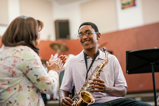 Teacher and student with a saxophone in a school hall setting