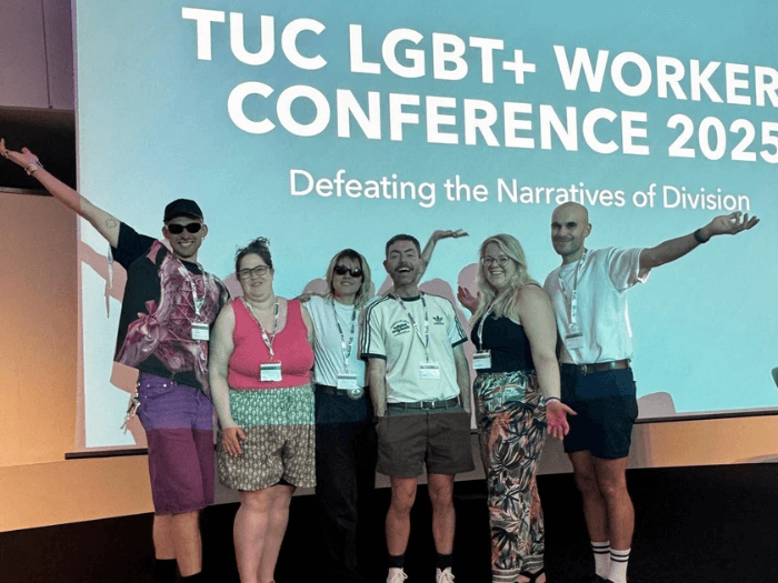 MU Head of ED&I John Shortell, with Regional Officer Simeon Scheuber-Rush and MU delegates, on the main stage in front of a blue screen saying “TUC LGBT+ Workers’ Conference 2025