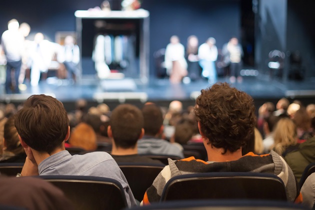 Photograph of audience of theatre goers watching a play.