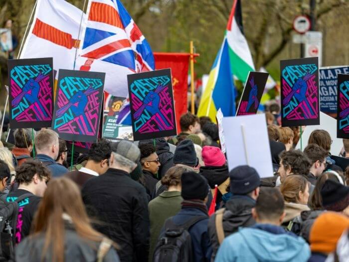 A crowd of protesters at a march. In the middle are matching placard held up that say 