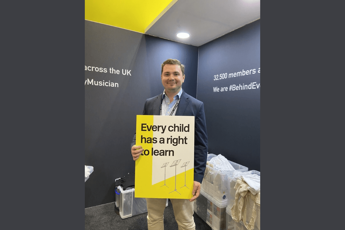 Tom Plater at the MU stand at 2022's Labour Party Conference, holding a sign saying 'Every Child Has the Right to Learn'.