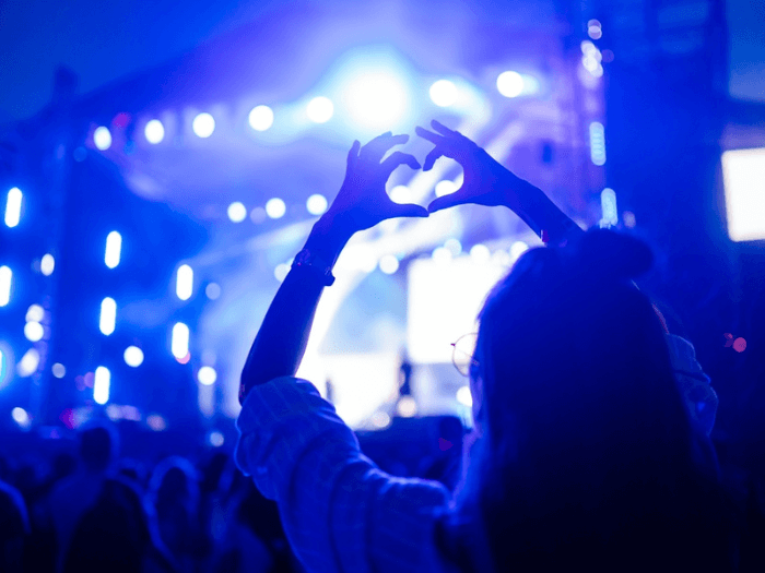 Person holding up heart shaped hands at a live gig.