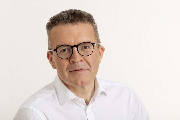 Photograph of Tom Watson, chair of UK Music and former deputy Labour leader. Tom is wearing a white shirt and glasses, sitting against a bright background.