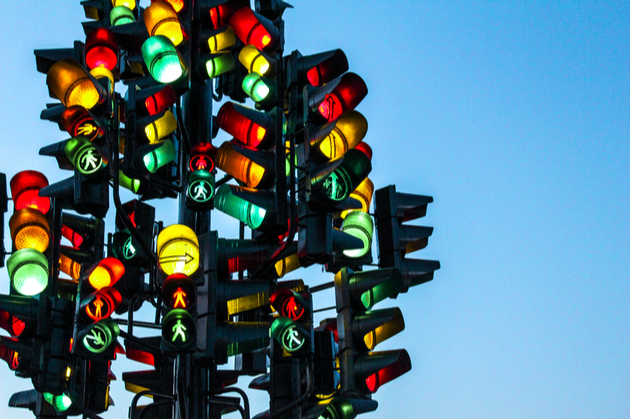 Photograph of multiple traffic lights set up in one gigantic and confusing tree of signals.