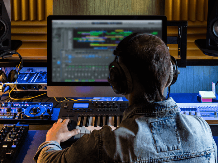 Male musician composing an electronic music score at a computer and laptop.