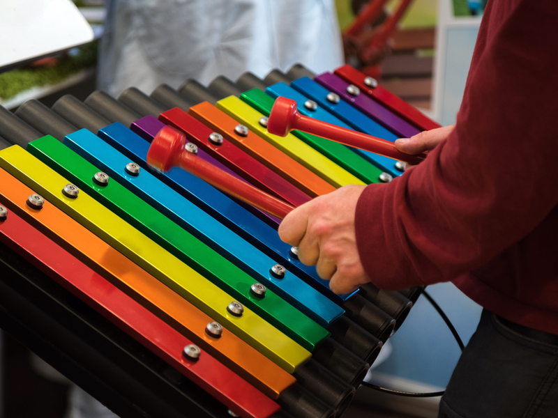 Photograph of a young person playing on a rainbow coloured instrument