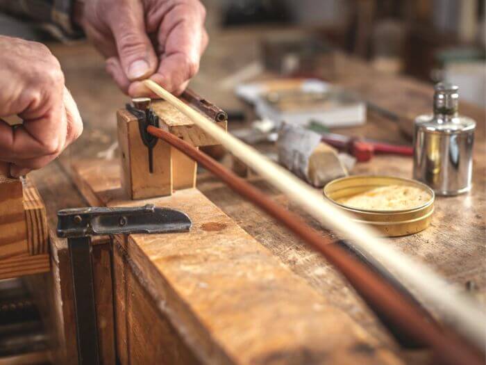 Hands of an instrument maker connecting the hair to the violin bow