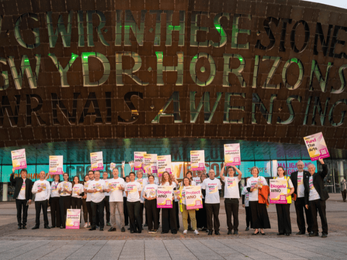 Welsh National Opera orchestra musicians standing outside the Wales Millennium Centre in Cardiff Bay.