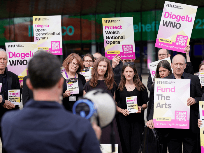 Members of the WNO orchestra stood outside the Wales Millennium Centre at a leafleting demo event in June. One person is holding a megaphone.